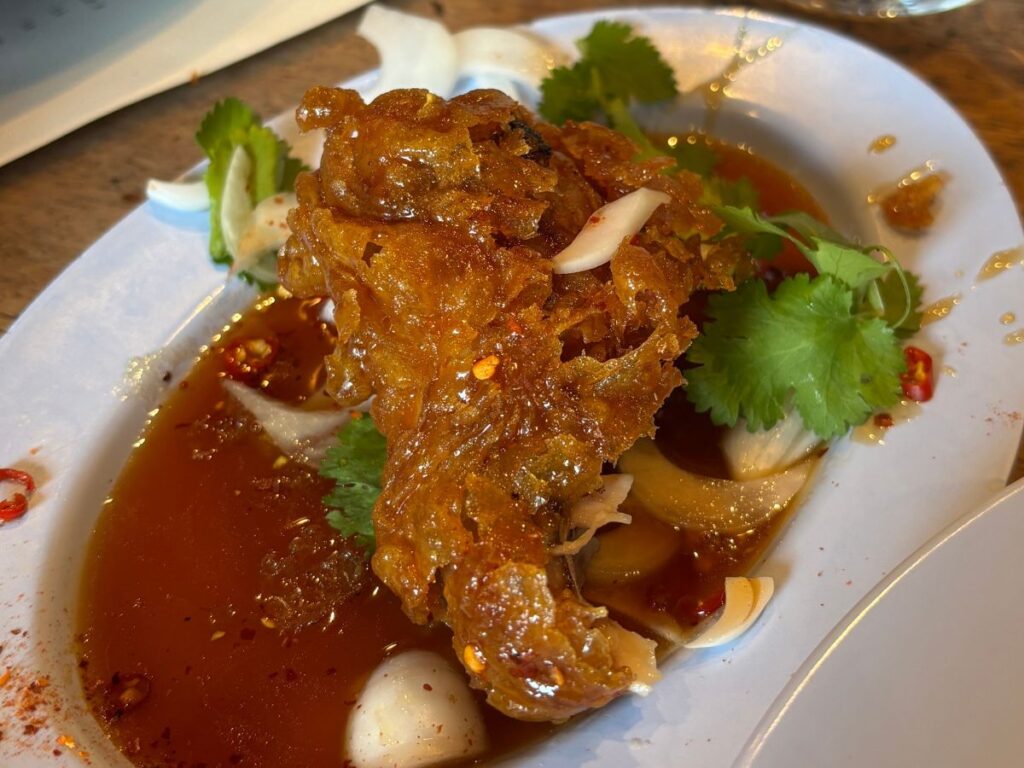 Crispy chili chicken wings served on a white oval plate with a green garnish of cilantro at Shoreditch's Smoking Goat restaurant
