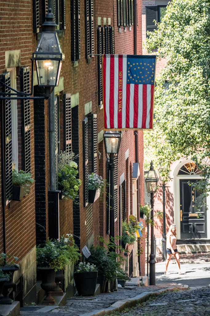 A charming historic street in Boston with classic brick buildings and a US flag.
