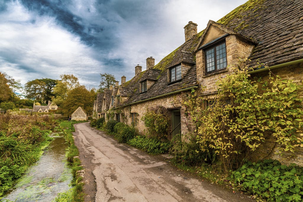 Picturesque stone cottages along a scenic road in Bibury, England, UK.