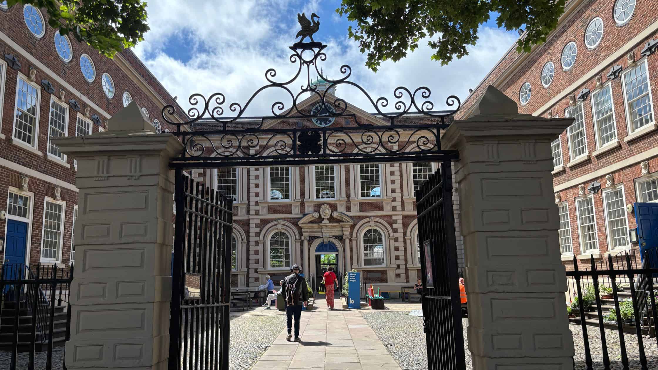 Gated entrance to Liverpool's Bluecoat Chambers historic building with ornamental ironwork and liverbirds.