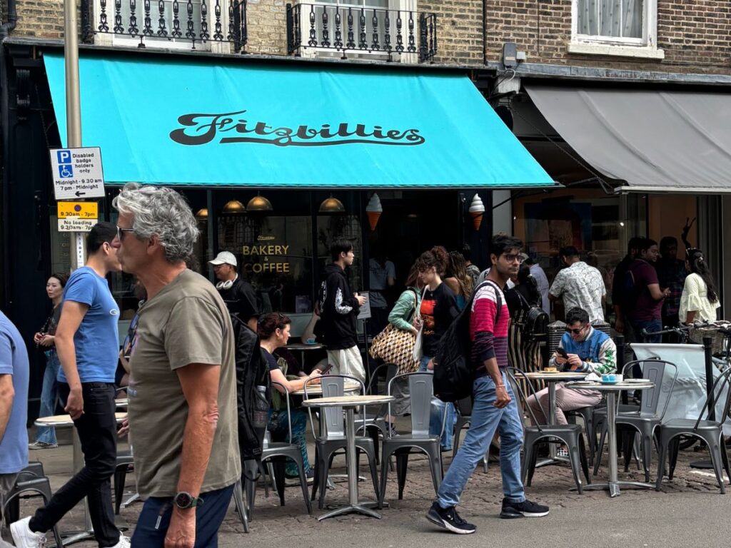 Front entrance of Fitzbillies bakery in Cambridge, England, featuring a light blue awning and matching lettering.