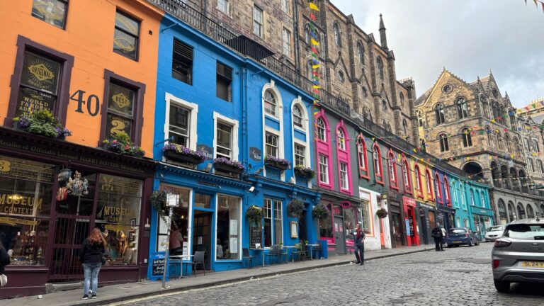Colorful streetscape of Victoria Street in Old Town Edinburgh with historic buildings and shops.