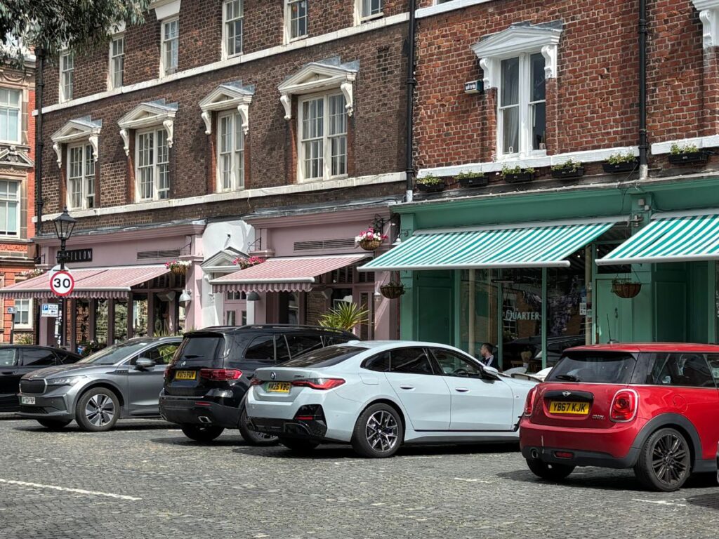 Colorful awnings under which there's bistro style street dining on Falkner Street Liverpool with Georgian buildings as a backdrop and cobblestones in the foreground.