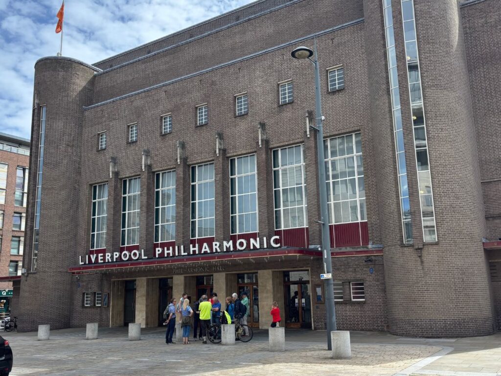Front exterior of the Art Deco Philharmonic Hall on Hope Street Liverpool, showing the striking 1939 facade designed by architect Herbert Rowse. Grey brick with windows above signage.