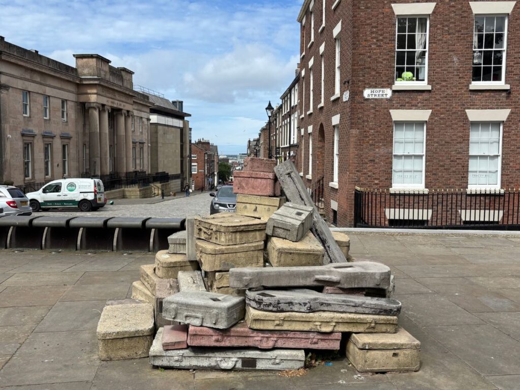 Case History street art installation on Hope Street in Liverpool's Georgian Quarter, featuring stone travel cases and instrument cases with Mount Street visible in the background