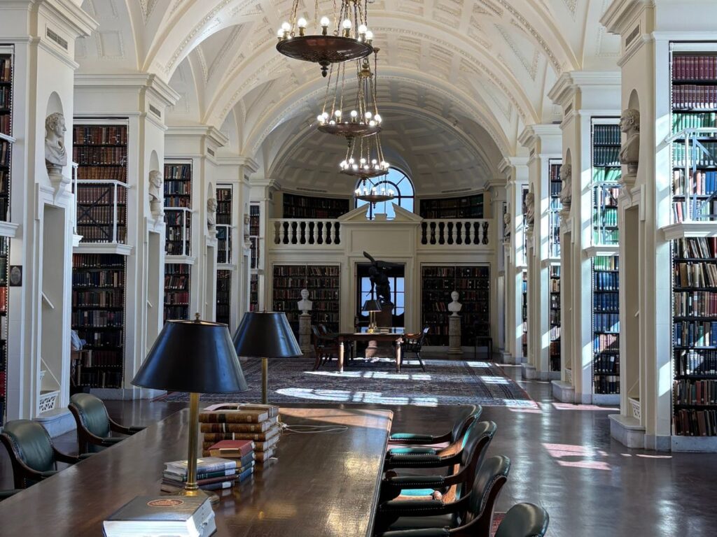 Reading room in the private library of the Boston Athenaeum on Beacon Street with long wooden reading table and greek revival interior.
