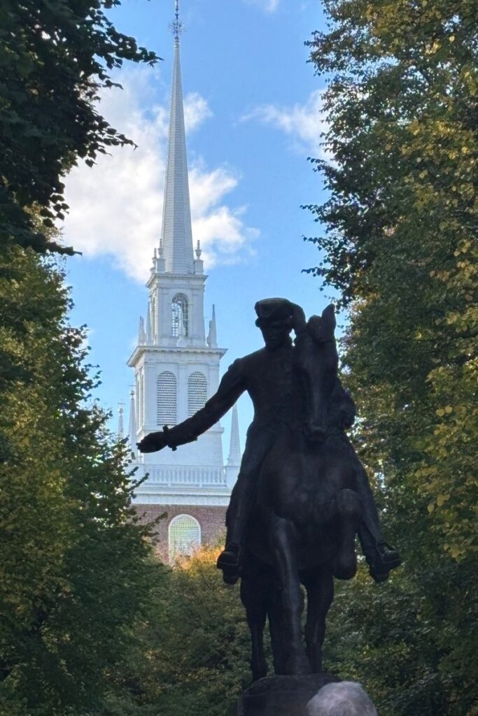 Paul Revere statue in Boston’s North End with Old North Church behind, framed by autumn-colored leaves.