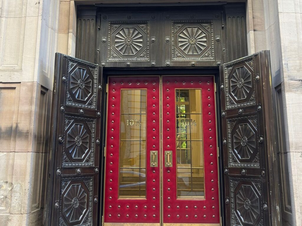 Red double doors with ornate ironwork at the entrance of the Boston Athenaeum private library on Beacon Street.