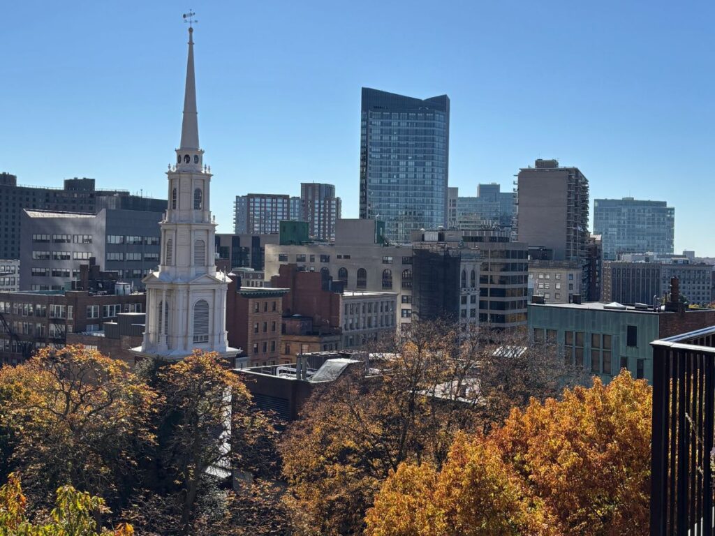 Boston skyline framed by fall foliage, viewed from the private upper level of the Boston Athenaeum Library, accessible only on guided tour.