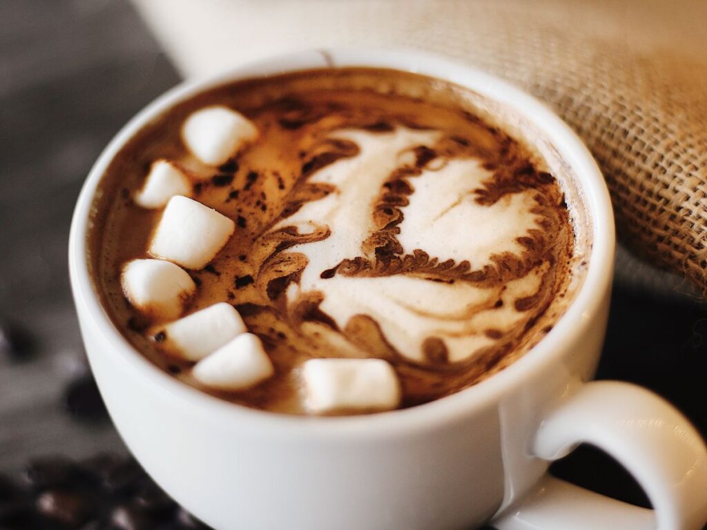 Cup of hot chocolate with marshmallows and cocoa heart decoration.