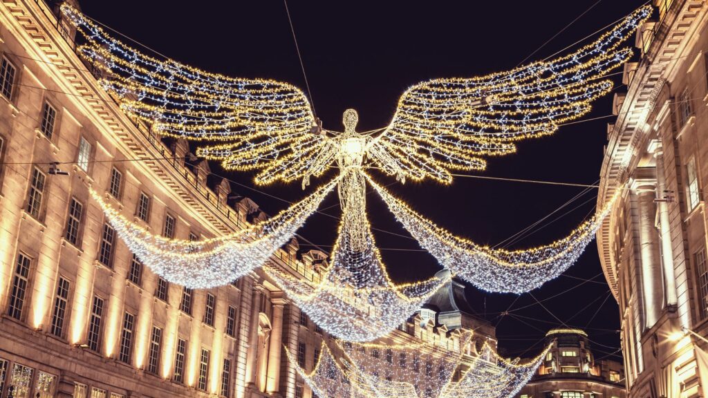 Regent Street London Christmas Lights as seen at night, featuring iconic Spirit of Christmas angels suspended above the street.