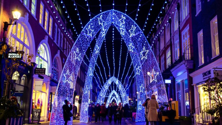 South Molton Street in London at night with blue Christmas lights. Arch in foreground and string lights overhead.
