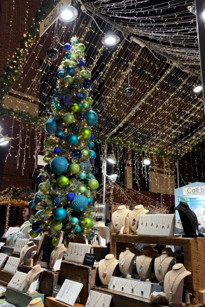 Brightly colored Christmas tree decorated with baubles at an indoor Christmas market.