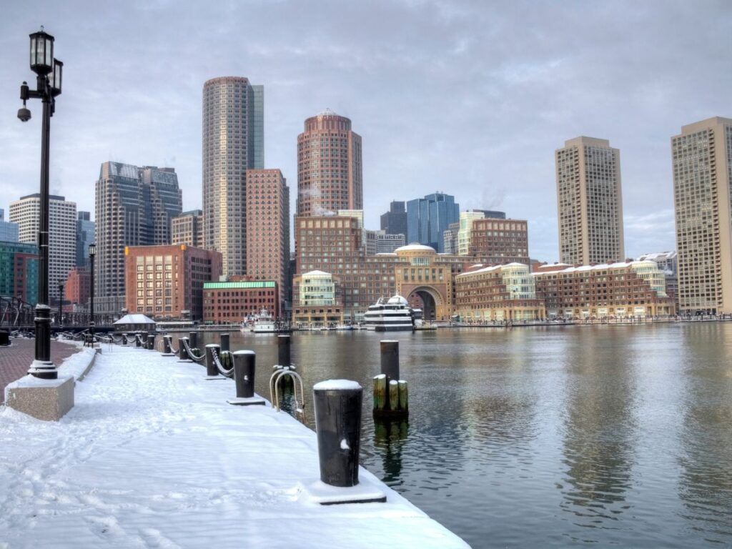 Snowy winter view of Boston Seaport District with waterfront and Boston Seaport Hotel in the background.