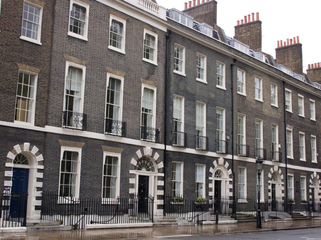 Front of Georgian row houses showing architectural period details around doorways on Bedford Square, London.