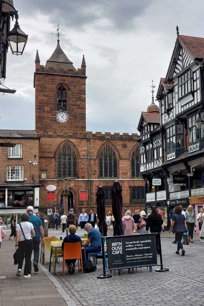 Red brick St. Peter's Church in Chester, England as viewed from Chester Cross with people on pedestrianized street.