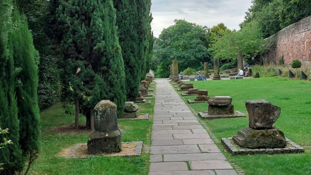 Roman Gardens in Chester looking towards the River Dee with central stone path and Roman artifacts either side.