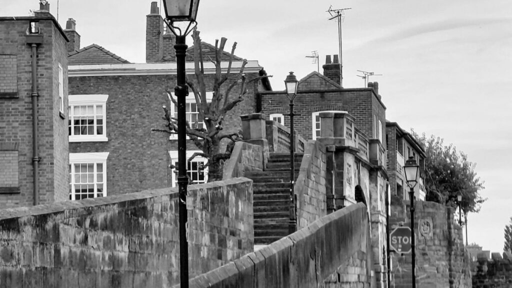 Section of the historic city walls in Chester, UK with Georgian buildings in the rear and a street as seen in fall.