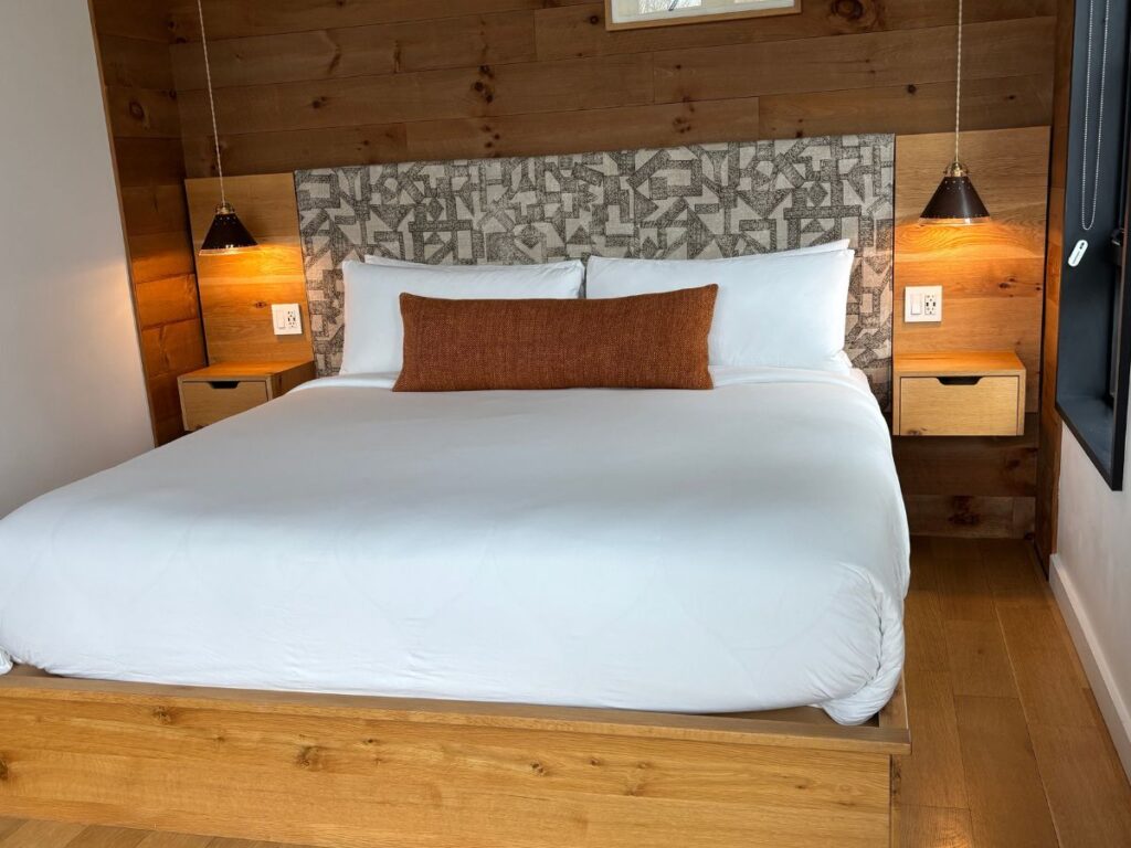 King bed with white sheets and orange decorative pillow at woodstock way hotel.