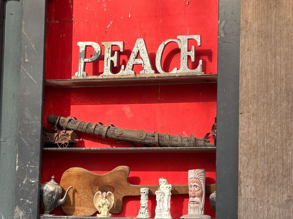Vintage art installation featuring wooden peace lettering and wooden carvings on a red background in Woodstock NY