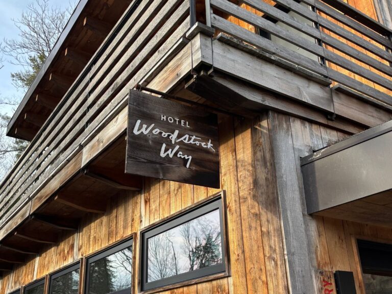 Wooden signage hanging outside entrance to the Woodstock Way Hotel in Woodstock, New York.