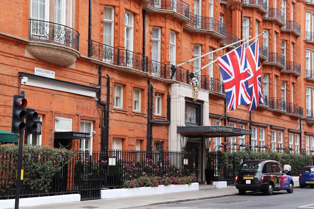 Exterior of classic London hotel on a busy street with Union Jack flags displayed.