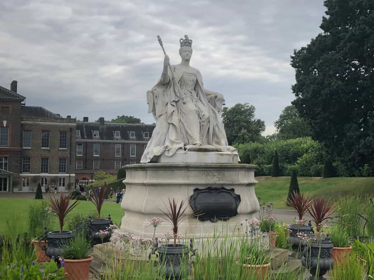 White marble statue of Queen Victoria in front of Kensington Palace in Kensington Gardens on a cloudy day in London