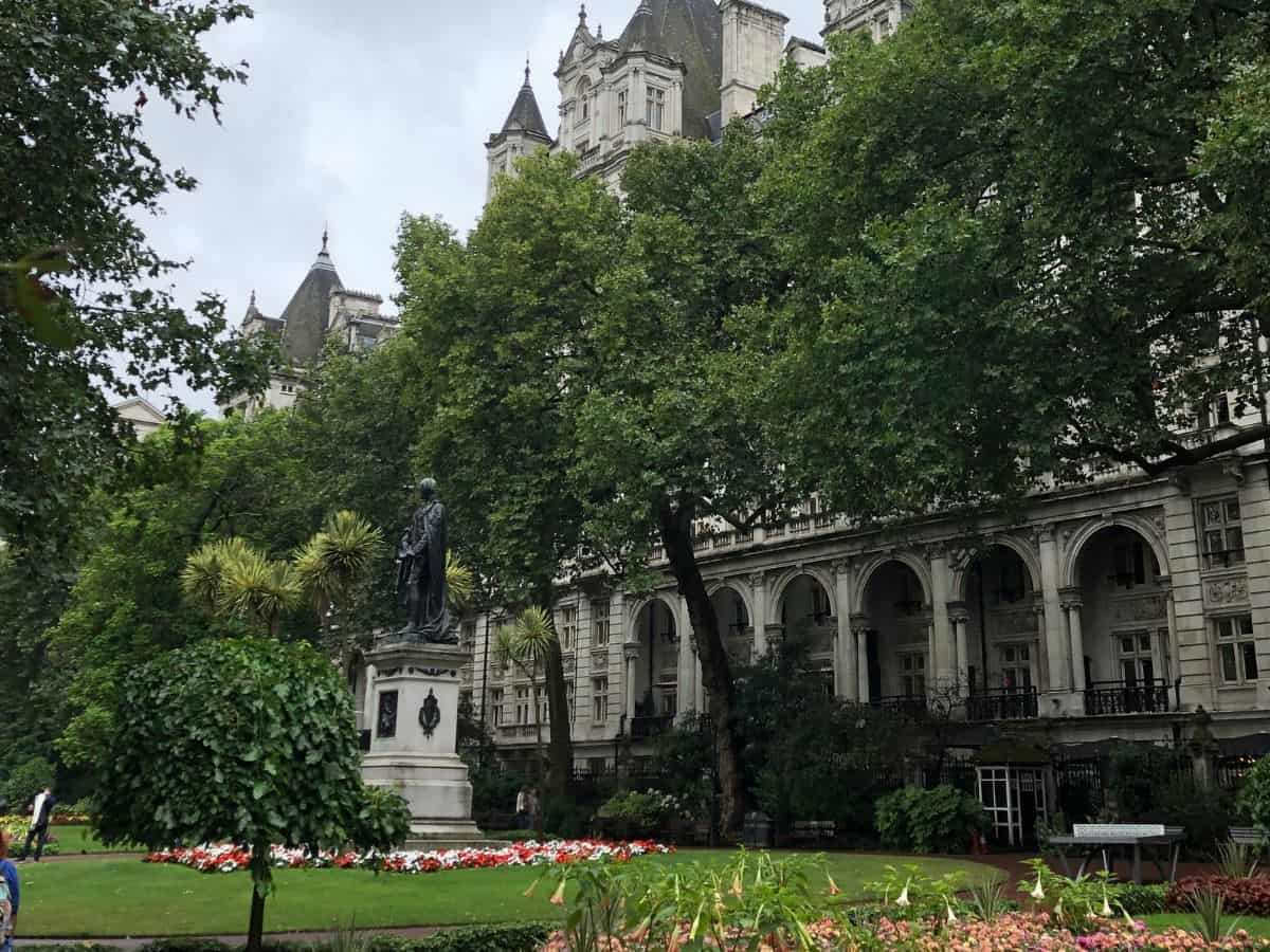 Lush Victoria Embankment Gardens in London with statue in foreground.