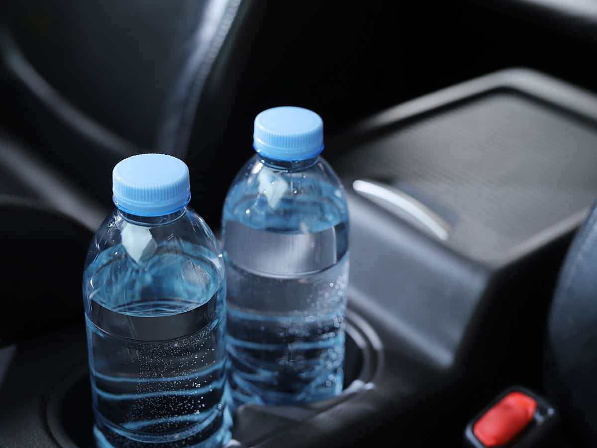 Inside view of a car with black leather interior and two water bottles in the cupholders to signal a welcome during an private airport transfer