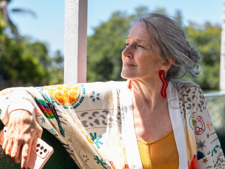 Woman over 50 with grey hair looking to the right and looking relaxed and at ease.