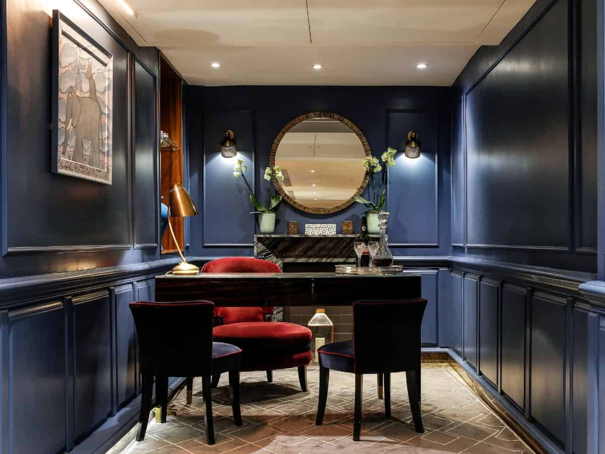 Guest services desk in atmospheric alcove of the Flemings Hotel in London with round mirror behind and plush seating.