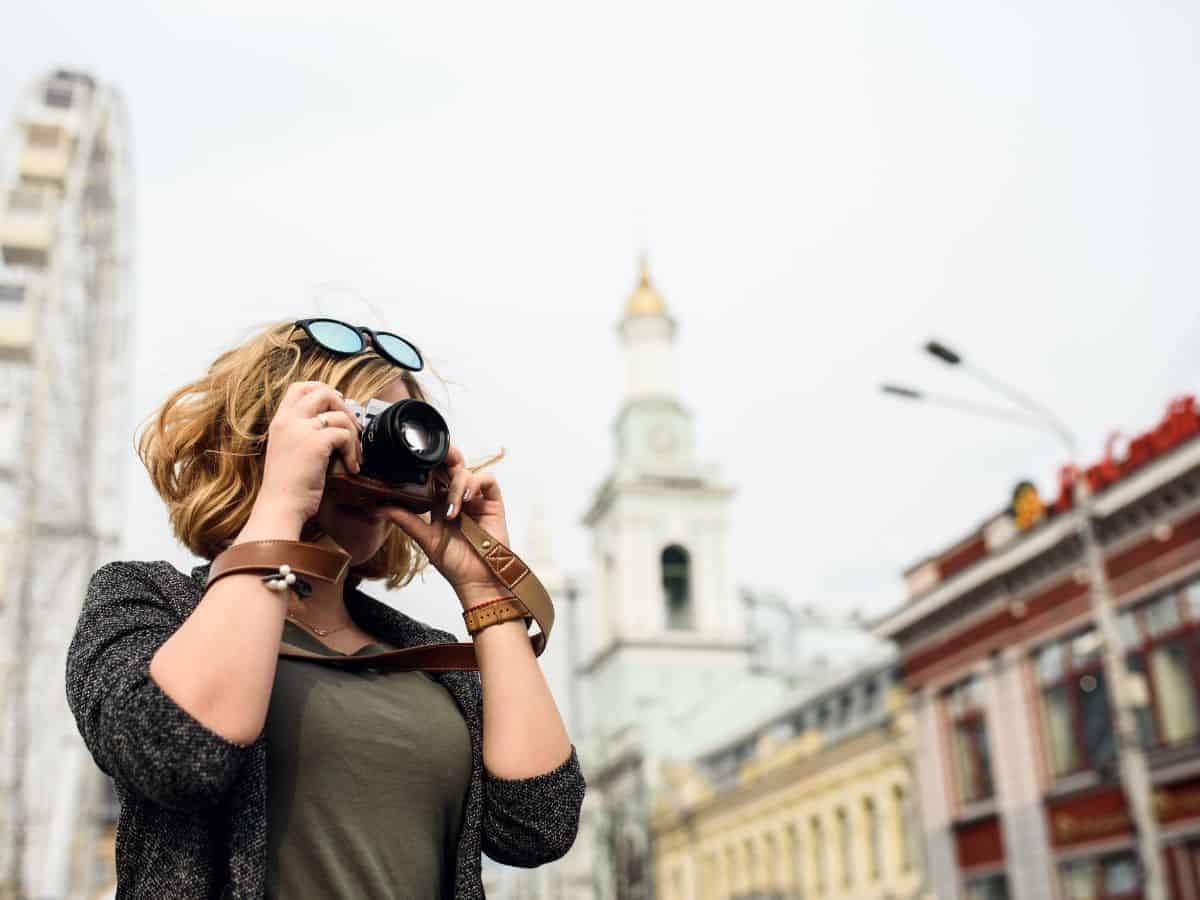 Middle aged woman with short hair taking a picture while sightseeing in an unknown location.