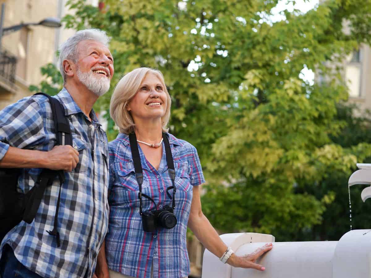 Couple in their late 50s/early 60s sightseeing. Man had grey hair and beart and wearing checked shirt and woman had a camera around her neck. Location unknown.