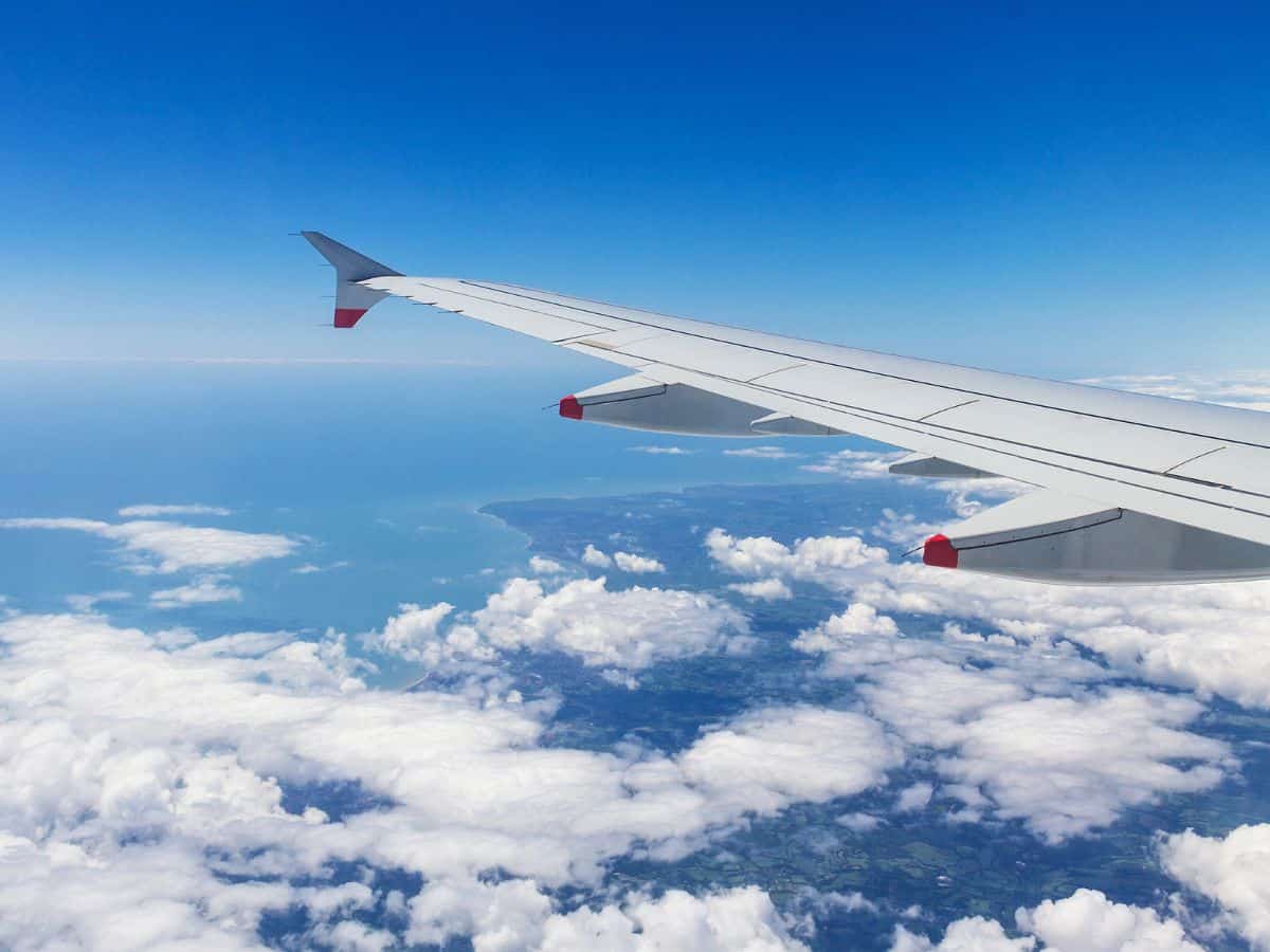 Blue sky and clouds as seen from the window of an aircraft at 30,000 ft with left wing in frame.